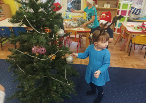 dziewczęta i chłopcy ubierają choinkę