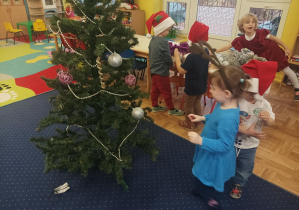 dziewczęta i chłopcy ubierają choinkę