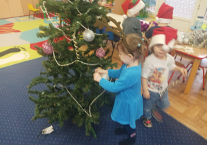 dziewczęta i chłopcy ubierają choinkę