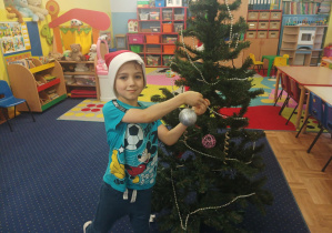 dziewczęta i chłopcy ubierają choinkę