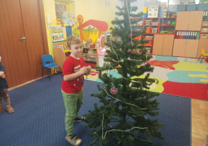 dziewczęta i chłopcy ubierają choinkę