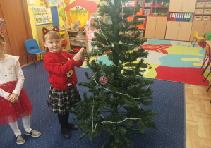 dziewczęta i chłopcy ubierają choinkę