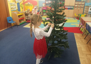 dziewczęta i chłopcy ubierają choinkę