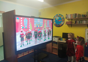 dzieci tańczą do muzyki przed tablicą interaktywną