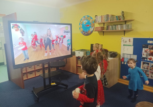dzieci tańczą do muzyki przed tablicą interaktywną