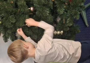 Chłopiec wiesza ozdoby na choince.