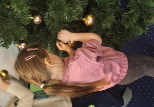 Dziewczynka wiesza ozdoby na choince.