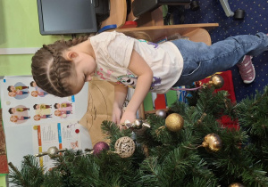 Dziewczynka wiesza ozdoby na choince.