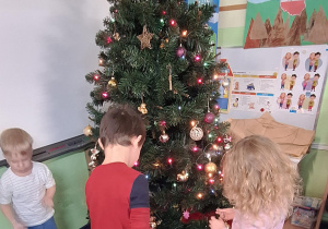 Chłopiec wiesza ozdoby na choince.