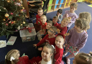 Dzieci siedzą przy choince.