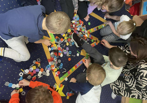 Dzieci układają choinkę z klocków.