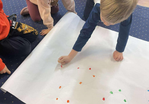 Dzieci malują farbami światełka na choinkę.