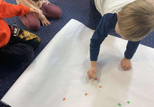 Dzieci malują farbami światełka na choinkę.