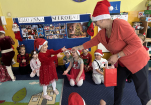 Pani rozdaje dzieciom prezenty od Świętego Mikołaja.