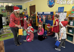 Pani rozdaje dzieciom prezenty od Świętego Mikołaja.