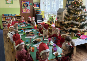 Dzieci siedzą przy stole, na którym leżą słodkości.