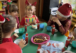 Dzieci siedzą przy stole i zjadają słodkości.