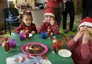 Dzieci siedzą przy stole i zjadają słodkości.