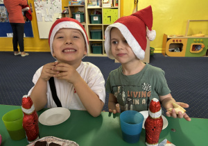 Dzieci siedzą przy stole i zjadają słodkości.