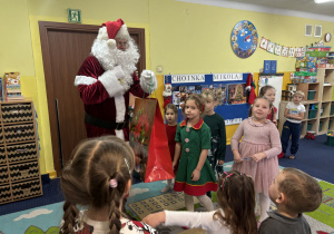 Mikołaj daje dzieciom prezent.