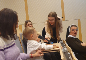 Chłopiec siedzi na widowni i odpowiada na pytanie.