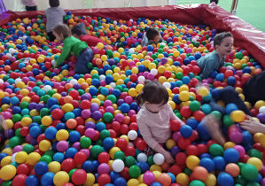 dzieci bawią się w basenie z kolorowymi piłkami