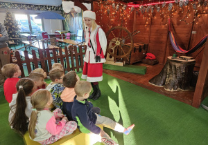 Dzieci słuchają elfa o monetach Świętego Mikołaja.