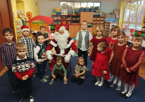 dzieci z grupy 2 pozują do zdjęcia z Świętym Mikołajem