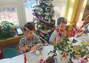 dzieci świętują wigilię klasową, siedzą przy stolikach, na których widać słodycze, owoce, soki