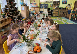 Dzieci siedzą przy stole i zjadają śniadanie.