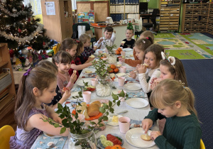 Dzieci siedzą przy stole i zjadają śniadanie.