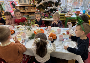 Dzieci siedzą przy stole i zjadają śniadanie.