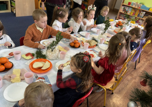 Dzieci siedzą przy stole i zjadają śniadanie.