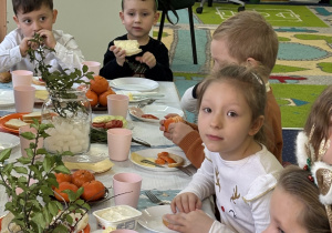 Dzieci siedzą przy stole i zjadają śniadanie.