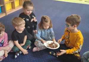 Dzieci siedzą w kole i oglądają herbatę.