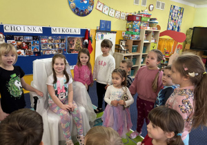 Dzieci ustawione w kole śpiewają "100 lat!".