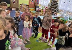 Dzieci ustawione w kole śpiewają "100 lat!".