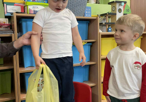 Chłopiec stoi na krześle podtrzymywany przez nauczyciela.