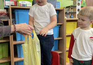 Chłopiec stoi na krześle podtrzymywany przez nauczyciela.