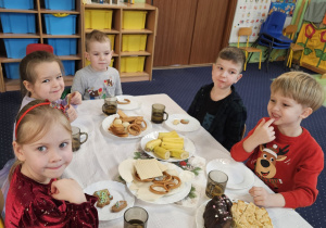 Dzieci siedzą przy wigilijnym stole.