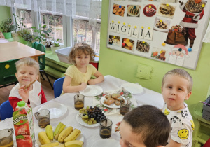 Dzieci siedzą przy wigilijnym stole.
