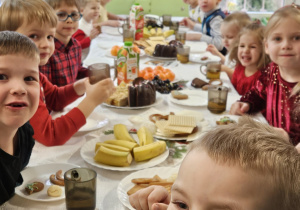 Dzieci siedzą przy wigilijnym stole.