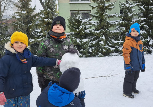 dzieci w ogródku lepią bałwana