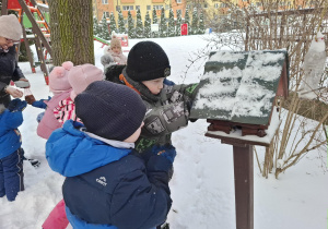 dzieci dokarmiają ptaki w ogródku przedszkolnym