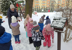 dzieci dokarmiają ptaki w ogródku przedszkolnym