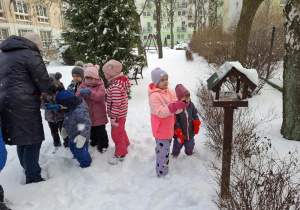dzieci dokarmiają ptaki w ogródku przedszkolnym