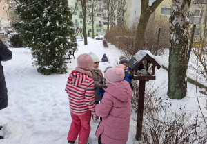 dzieci dokarmiają ptaki w ogródku przedszkolnym