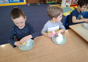 eksperymenty ze śniegiem, dzieci mają na talerzykach śnieg i różne akcesoria