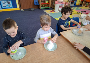 eksperymenty ze śniegiem, dzieci mają na talerzykach śnieg i różne akcesoria