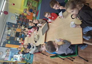 dzień popcornu w grupie 1, dzieci przy stolikach jedzą popcorn